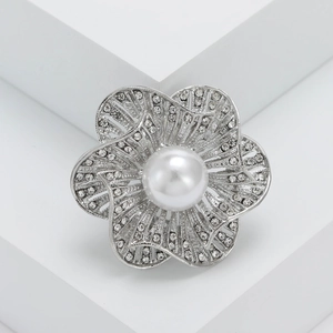 Macro view of flower brooch with large white pearl and sparkling crystals on silver petals