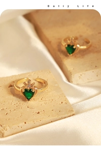 Dettaglio dell'anello corona dorato con zircone verde su sfondo di pietra naturale