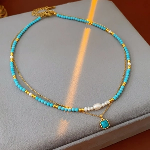 Dettaglio di collana a doppio strato in turchese e perle con ciondolo quadrato