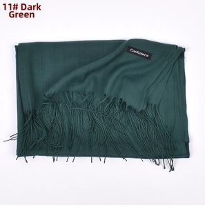 Close-up of fine cashmere texture and long fringe details on this dark green winter scarf