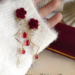 Detail of red rose tassel earrings with pearls and water drop charms on a soft fabric
