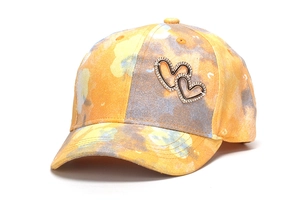 Close-up of colorful tie-dye baseball cap featuring glittering fabric and rhinestone hearts