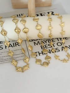 Macro detail of 18k gold plated stainless steel shell and starfish charm necklaces