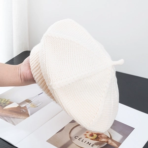 Detailed macro view of cream white knitted beret with soft thick wool texture