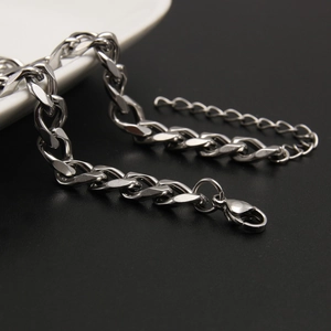 Silver stainless steel Cuban chain necklace with lobster clasp on ceramic surface