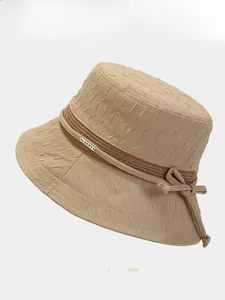 Détail d'un chapeau de soleil kaki plissé avec ruban tressé et étiquette Lucky dorée