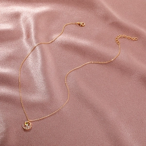 Elegant gold moon pendant necklace with yellow bead and rhinestones on pink satin
