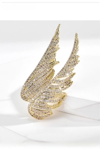 Macro detail of gold plated wing brooch with shimmering white cubic zirconia stones