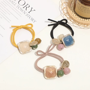Detailed view of elastic hair ties with square resin accents in yellow, black, and lotus pink