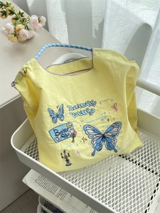 Floral embroidered tote bag with blue butterfly detail and plaid handles in cream yellow