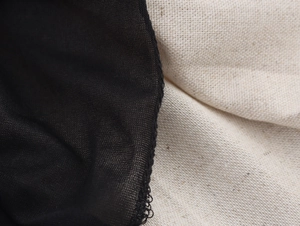 Macro detail of the contrast between black mesh fabric and cream linen texture