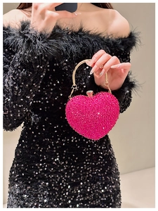 Close-up of heart-shaped evening bag featuring fuchsia rhinestones and gold ring handle