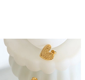 Close-up of vintage heart stud earrings with golden embossed texture on white display