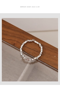 Macro shot of silver elastic beaded ring with hammer texture finish and square beads