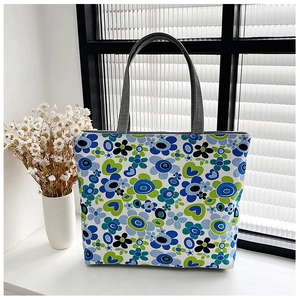 Close-up of floral print canvas tote bag featuring durable grey handles and blue patterns