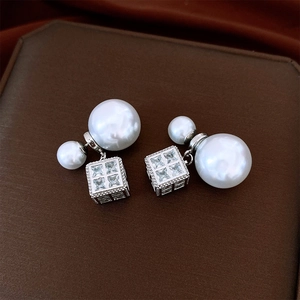Macro view of silver earrings featuring double pearls and a cubic zircon pendant