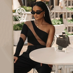 Detail of asymmetrical black bodysuit with mesh paneling and one-shoulder long sleeve