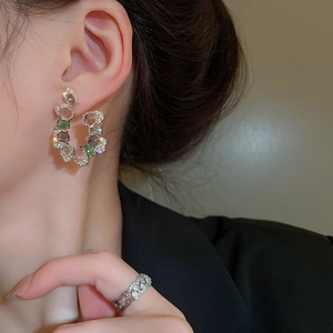 Detail shot of a model wearing colorful gemstone U-shaped earrings and a silver zircon ring