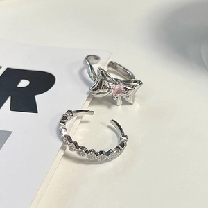 Detailed shot of silver bow ring with pink zircon and matching clear stone band
