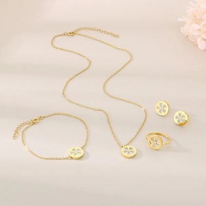 Detailed set of gold floral jewelry with white inlay on a soft beige background