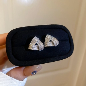 Macro shot of silver triangle stud earrings with zircons in a black velvet box