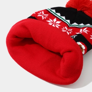 Close-up of red knitted Christmas hat with white snowflake patterns and soft pom-pom