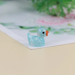 Detailed macro shot of a mini resin duck ornament with blue glitter and translucent finish