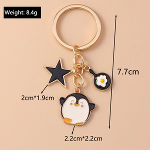 Detail of penguin keychain with gold star and frying pan charms showing size and weight