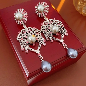 Détail de boucles d'oreilles vintage argentées avec strass roses et perles grises