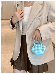 Close-up of blue mini jelly bag with woven texture and gold chain on beige blazer