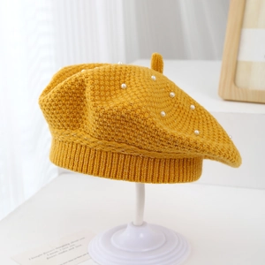 Detailed close-up of yellow knit beret with white pearls and soft textured finish