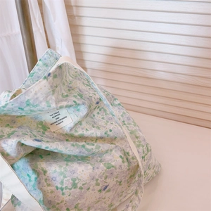 Macro detail of floral cotton tote bag with a white shoulder strap and text label