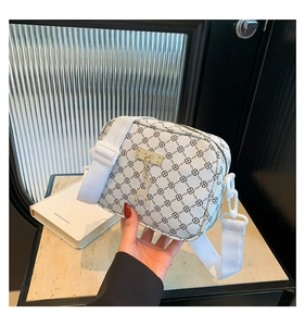 Detail of white monogram crossbody bag with golden hardware and wide fabric strap