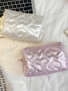 White and pink heart quilted makeup bags set on elegant white textured fabric