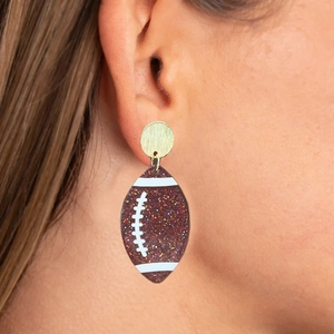 Macro view of brown glitter rugby ball dangle earring on golden stud fitting
