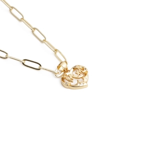 Detailed close-up of gold heart-shaped pendant with MOM lettering and zircon stones