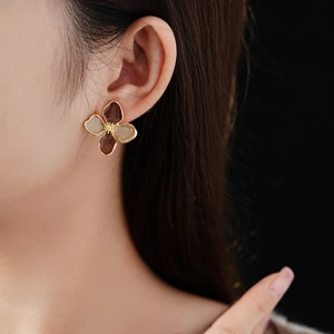 Close-up of vintage flower earrings with brown enamel and gold plating on a model