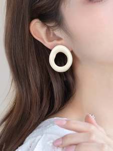 Close-up of cream oval resin earring on model with elegant lace top and hair detail