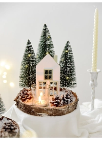 Cozy Christmas scene with wooden house, mini tree, and pine cones on a rustic tray