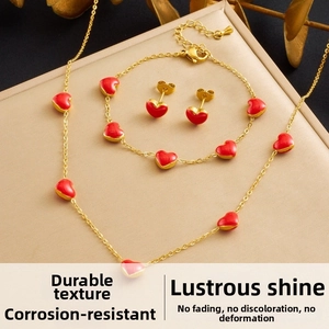 Detail of gold-plated stainless steel jewelry set with red heart enamel pendants