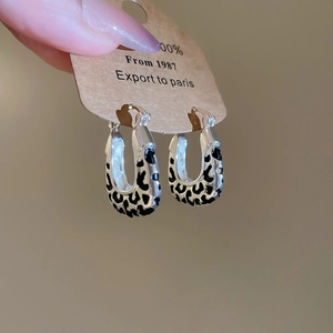 Close-up of vintage leopard print square hoop earrings on a vintage paper tag