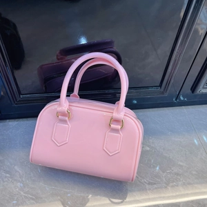 Detail view of pink jelly Boston bag with glossy finish and gold metal hardware