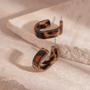 Detailed shot of tortoiseshell resin C-shaped hoop earrings on natural stone surface