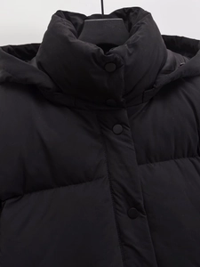 Detail der schwarzen Kapuzenpufferjacke mit Reißverschlussschutz und matter Faser