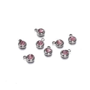 Détail macro de pendentifs ronds en métal argenté avec cristaux roses pour bijoux artisanaux