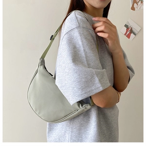 Detail of adjustable strap and gray-green nylon crescent bag shown on female model