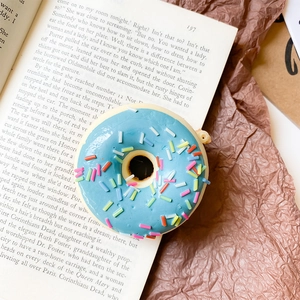 Detail shot of a blue 3D donut phone grip with colorful sprinkles on a vintage book