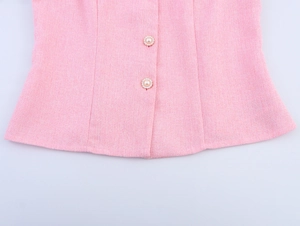 Nahaufnahme von rosa Tweed-Weste mit feinen Perlenknöpfen und gewebter Textur
