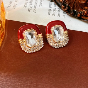 Macro shot of vintage gold earrings with deep red glaze and center rectangular zircon