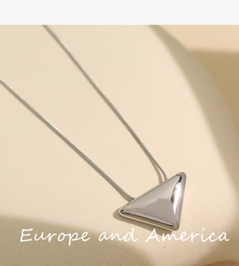 Detail of minimalist silver triangle pendant with snake chain on aesthetic display